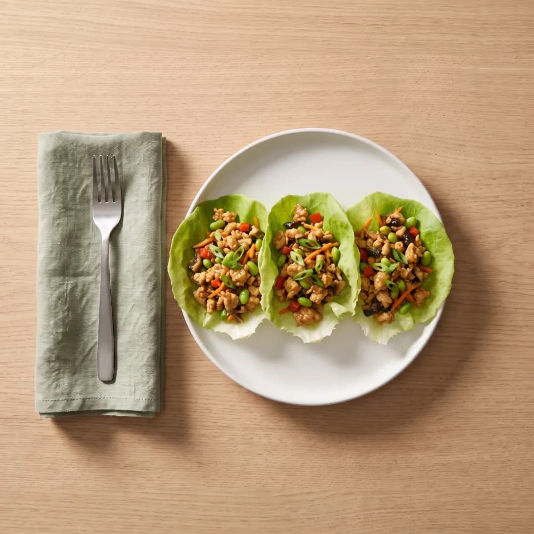 Three chicken lettuce wraps on a white plate