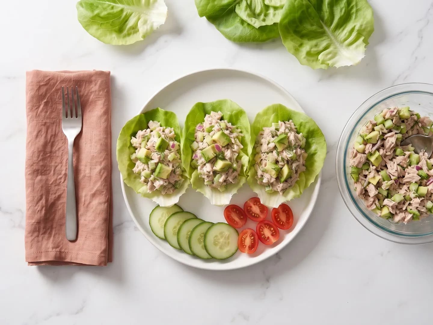 Tuna salad lettuce cups beside a bowl of tuna salad, seen from above