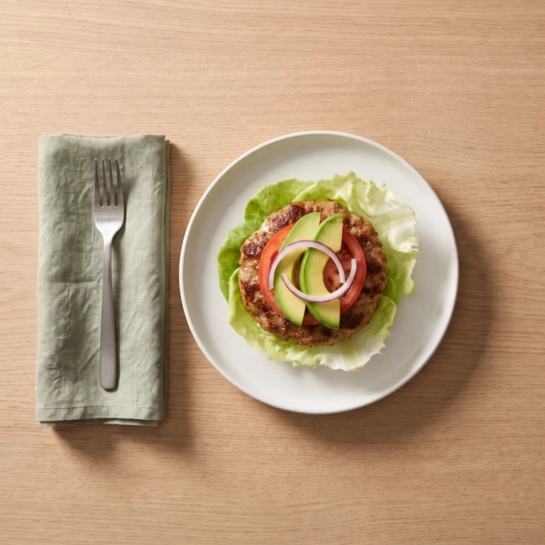Turkey burger wrapped in lettuce with tomato and avocado