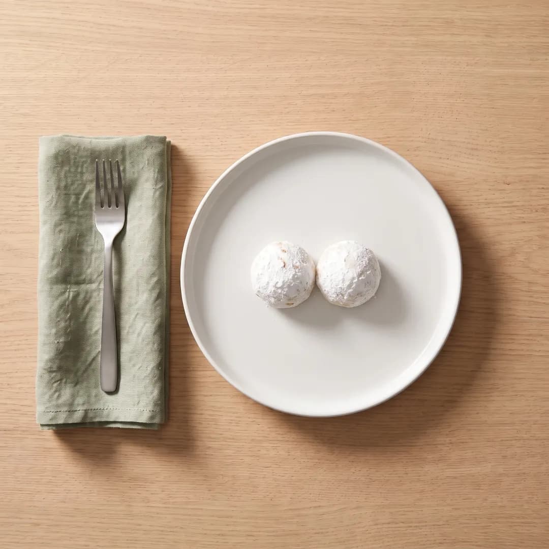 Two almond flour snowball cookies on a white plate