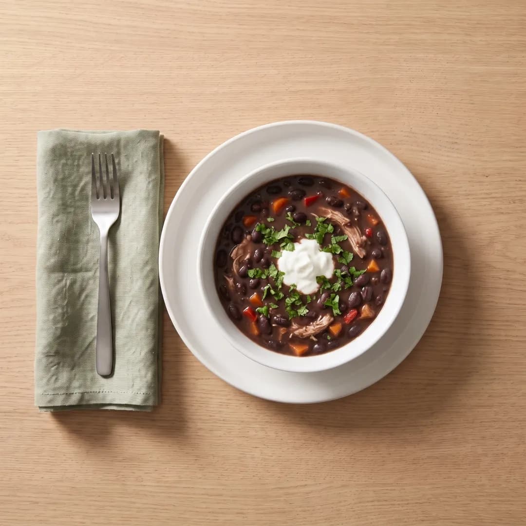 Bowl of black bean soup with chicken, yogurt and cilantro