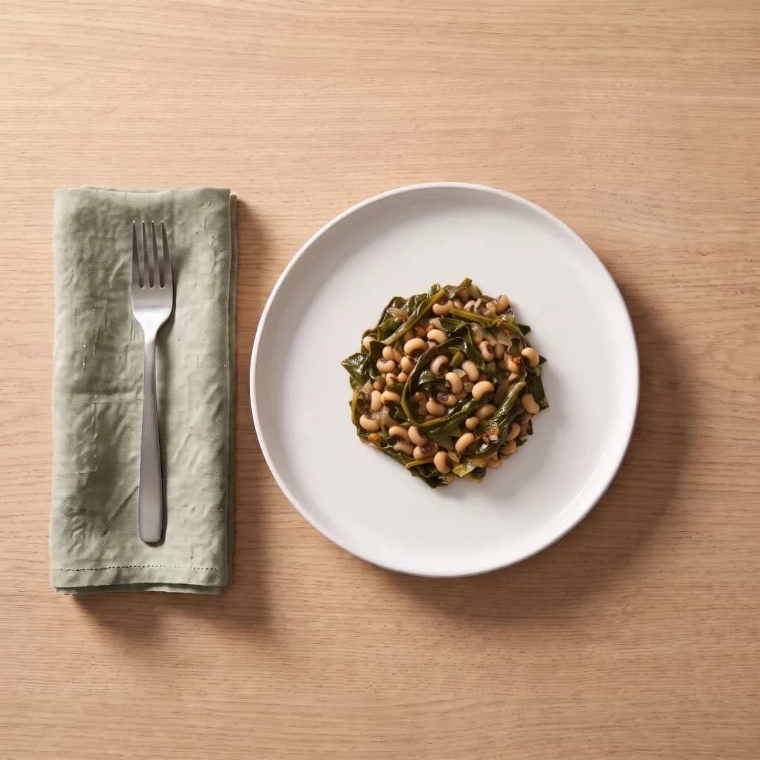 Black-eyed peas and collard greens on a white plate