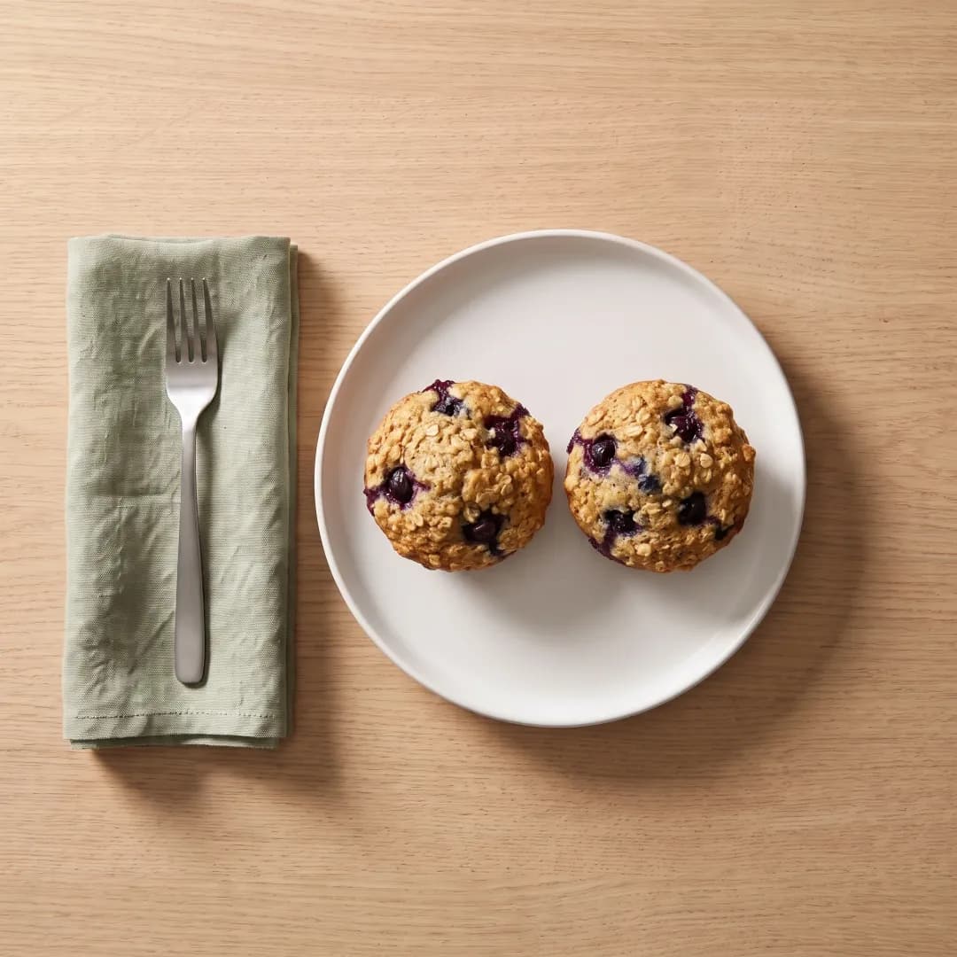 Two blueberry protein muffins on a white plate