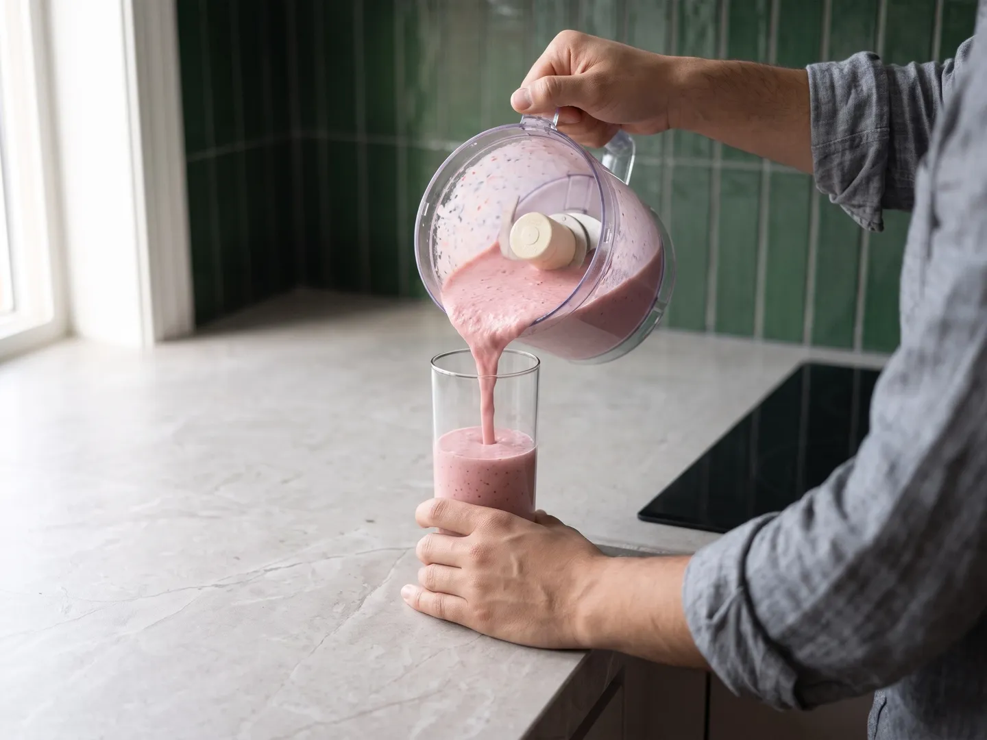 Pouring a protein smoothie into a tall glass